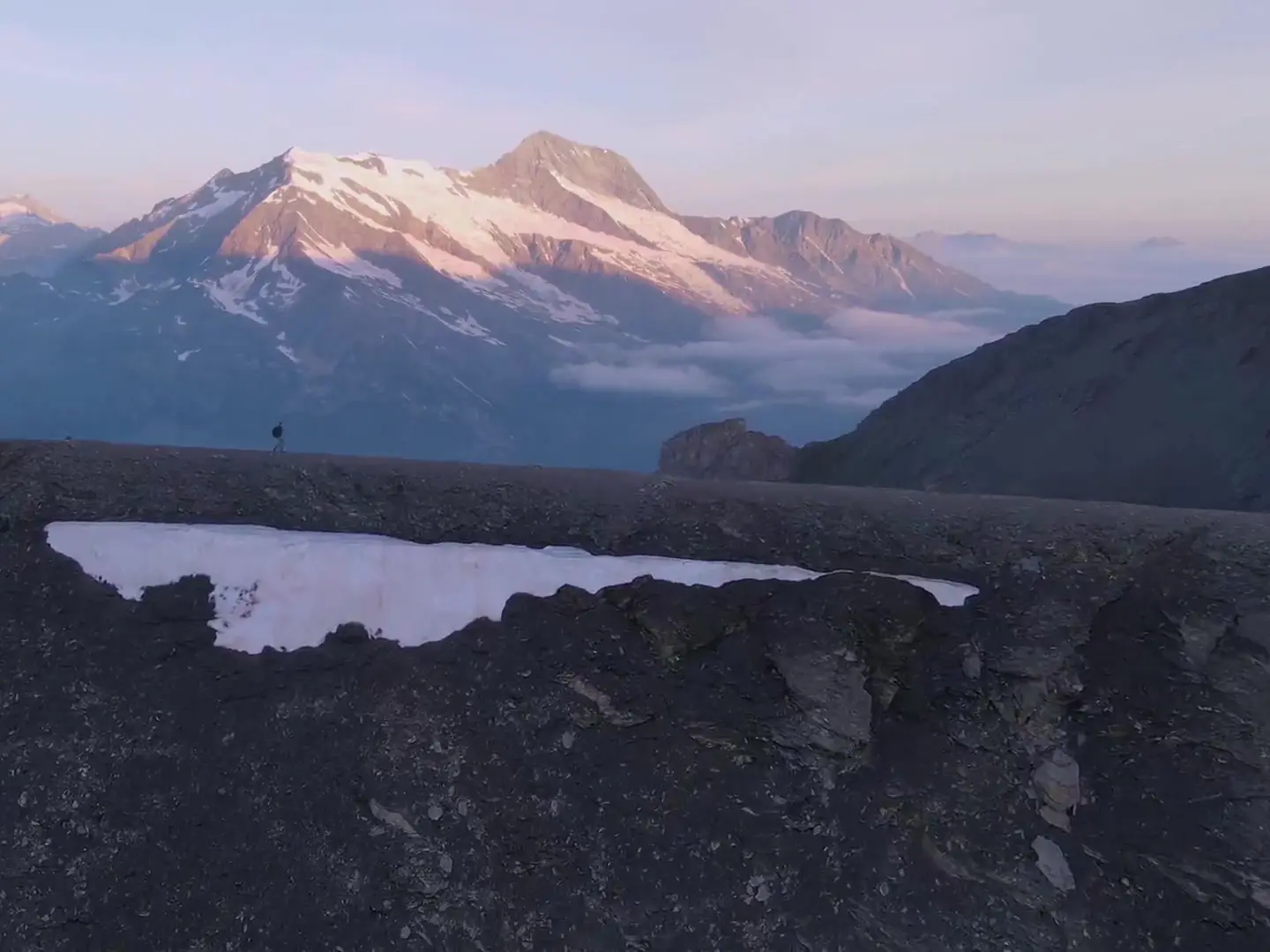 Crêtes calcaires découpées sous un ciel dégagé, versants d’alpage en contrebas.