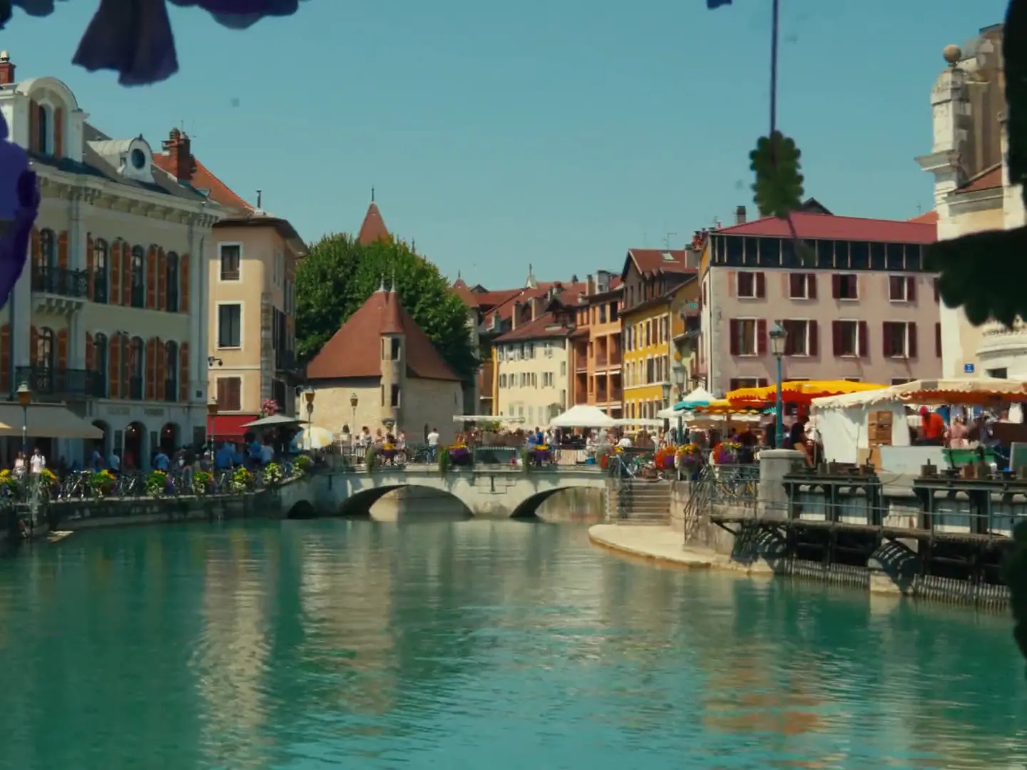 Le Palais de l'Isle et son pont de pierre sur le canal du Thiou, terrasses fleuries de la vieille ville d'Annecy.